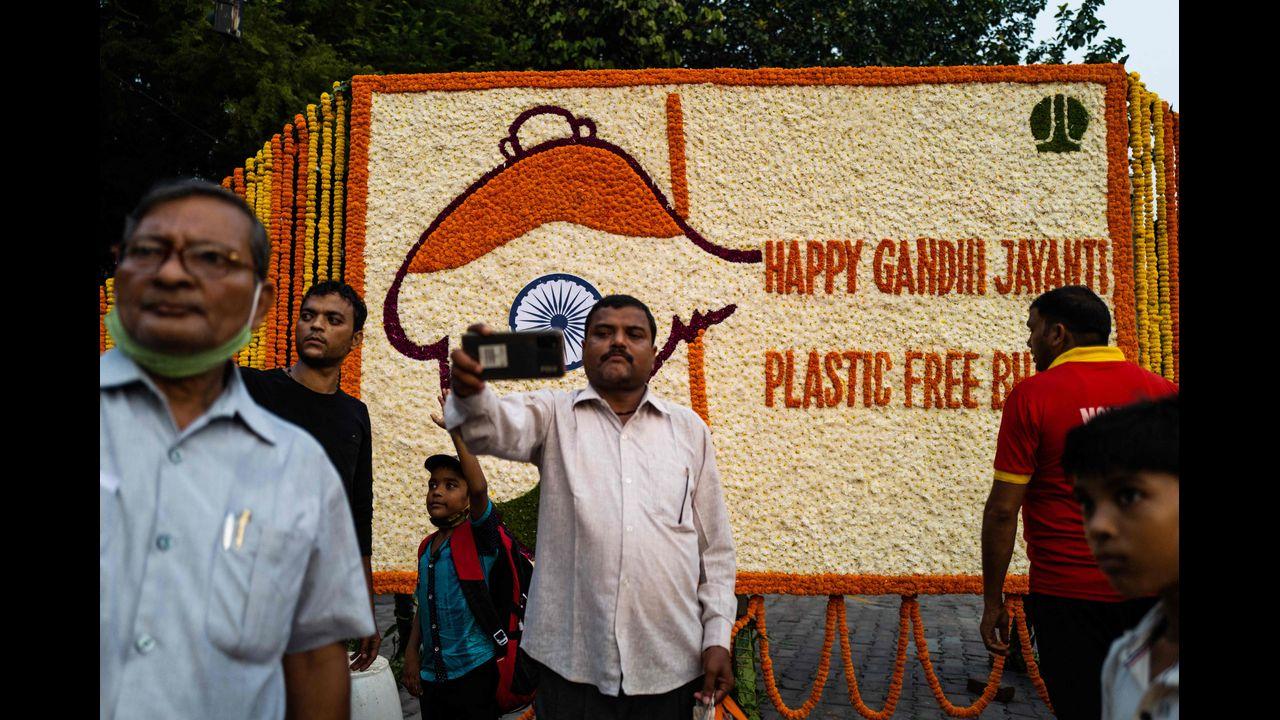 People take selfies in front of a floral arrangement on the eve of ‘Gandhi Jayanti’ marking the birth anniversary of India’s father of the nation Mahatma Gandhi besides a street in New Delhi. Pic/AFP